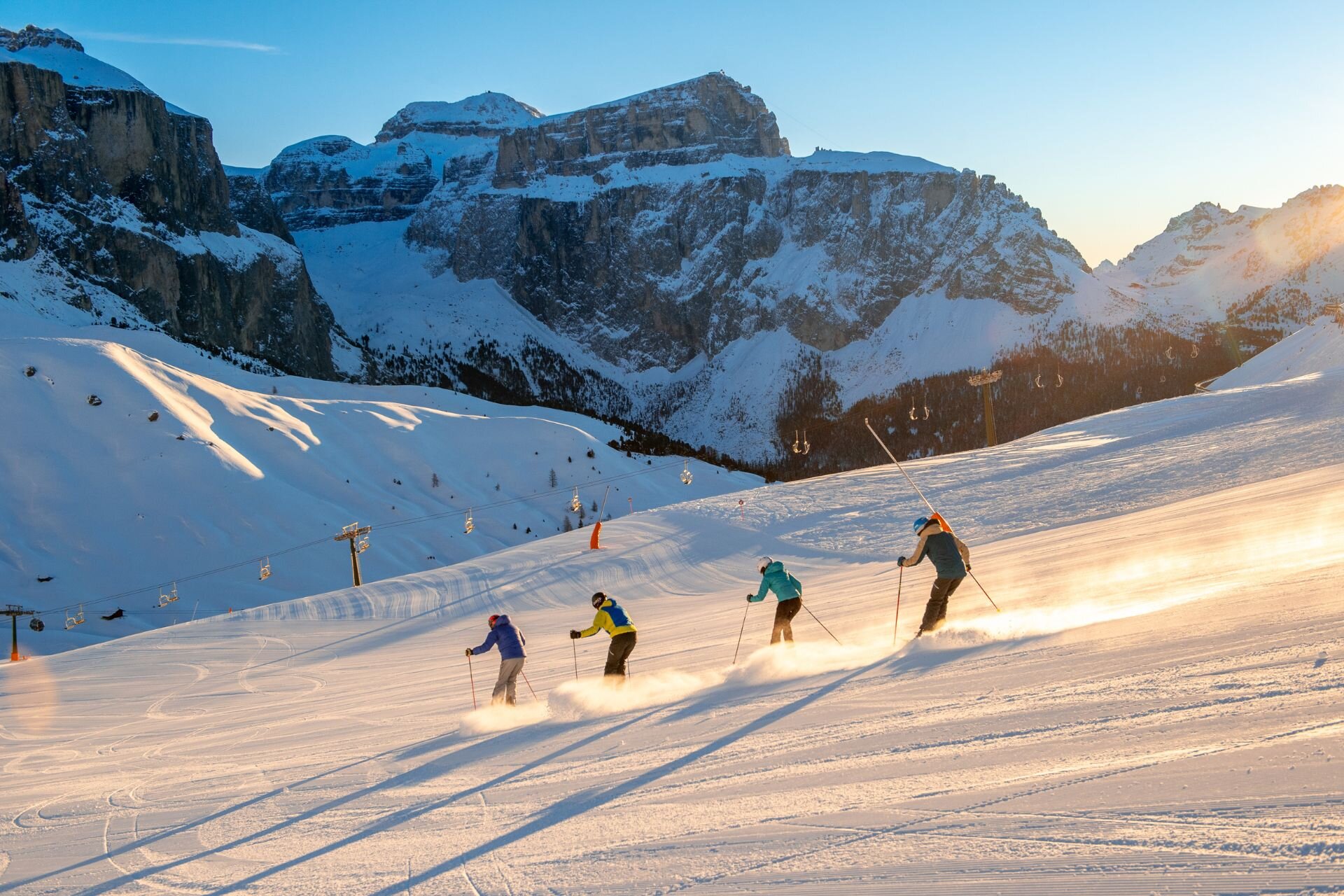 Quattro persone sciano all'aba sulle piste della Val di Fassa con vista sul Pordoi | © Archivio Immagini ApT Val di Fassa - Mattia Rizzi